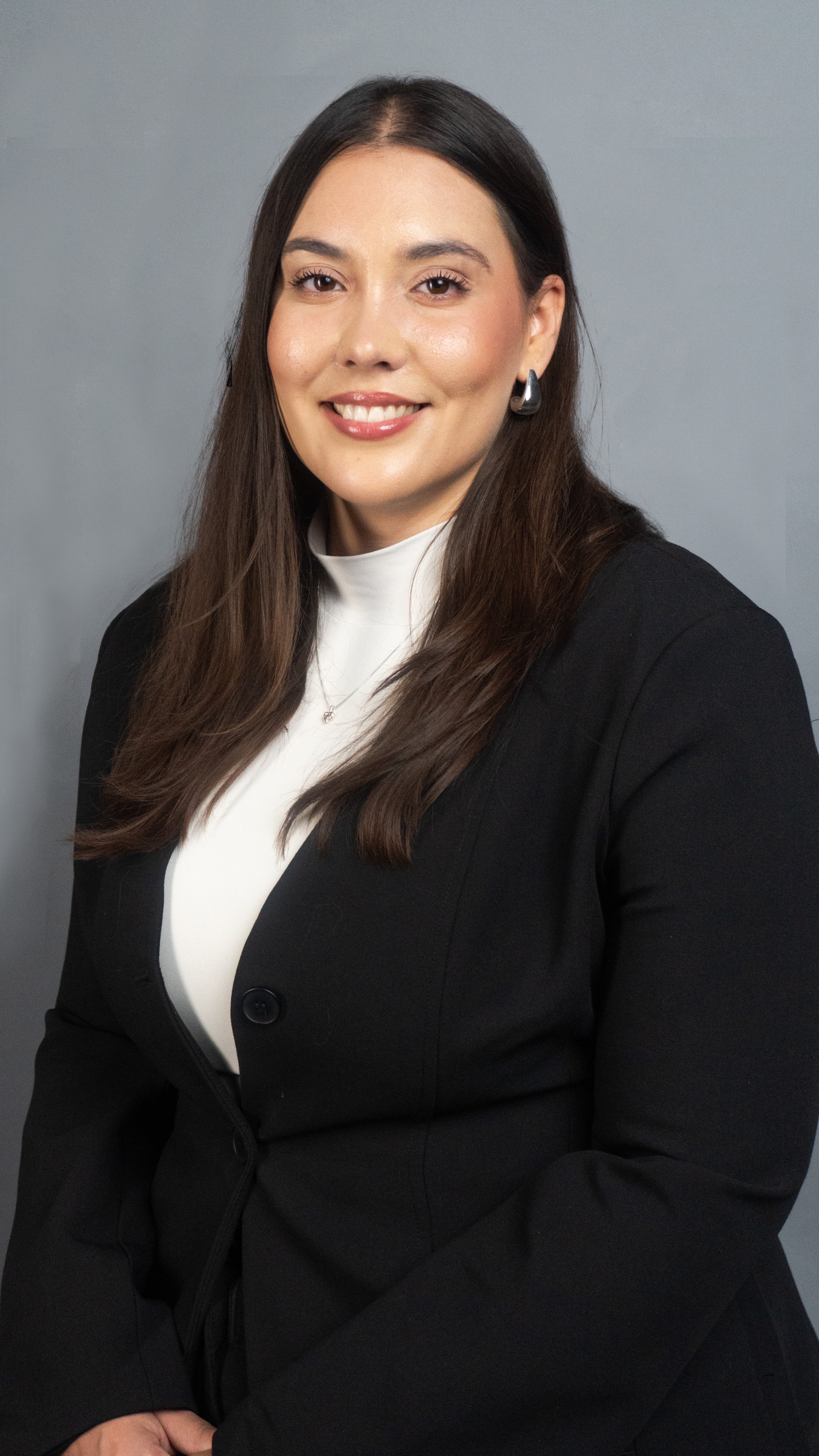 Woman wearing a black blazer over a white shirt against a gray background for professional picture